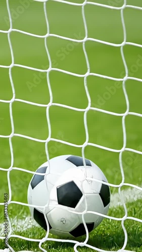 Detailed shot of a soccer ball swiftly striking the goal net. The accurate shot results in a goal being scored in a football game on a lush green field, captured in slow motion