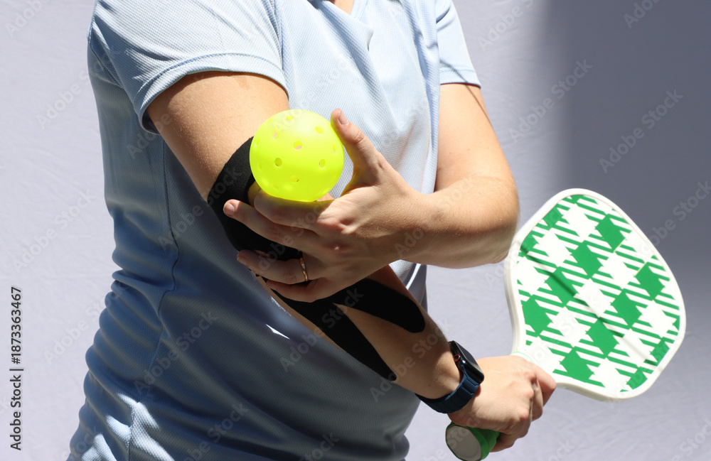 Fototapeta premium Caucasian woman playing pickeball with a Kinesio in the elbow and with pain in the elbow