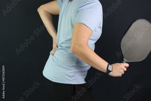 Caucasian woman playing pickeball with a lumbar pain and putting the hand in the pain region