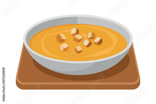 A bowl of creamy soup with croutons on a wooden board