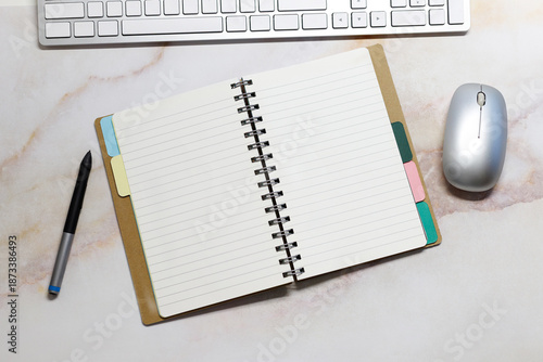 An open weekly planner on an office desk near a keyboard and stationery. Top view,