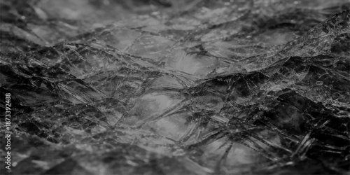 Abstract black and white texture featuring a cold winter pattern of ice and snow on a wet stone surface with a flowing river stream