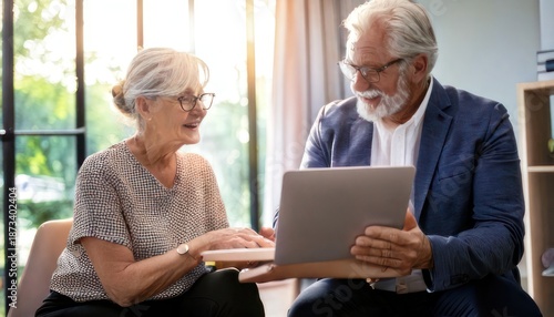 Senior couple using laptop together at home, discussing something.