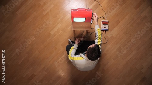 Person playing vintage video game with a classic console and smashing the old portable television screen out of frustration, attempting to fix connectivity issues