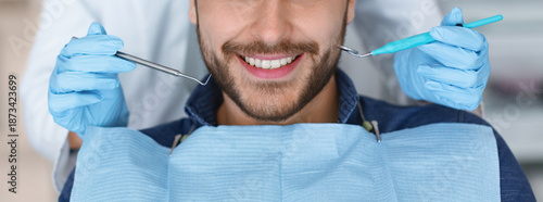 Bild auf Leinwand Cropped of smiling bearded man and dentist hands in blue robber gloves with dental tools, panorama