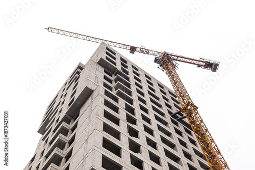 Construction of a high-rise building with a crane working on the top floor in an urban area