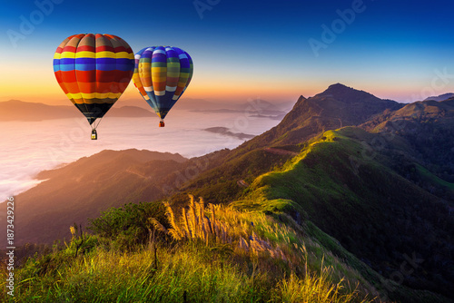 Landscape of morning fog and mountains with hot air balloons at sunrise.