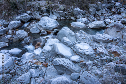 Schilderij op canvas Wide view of a dry riverbed filled with grey granite rocks covered in winter frost