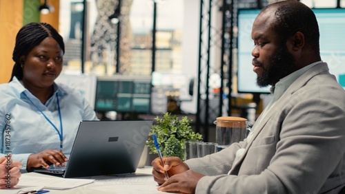 Slika na platnu Black male candidate adds signature on employment document for legal terms agreement during HR meeting, finalizing the hiring process and being excited about a new career start