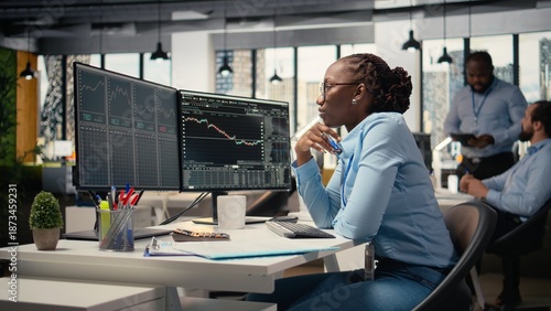 Forex expert in office looking over candlestick charts on screen to assess stock market volatility. African american woman in hedge fund company reading investment reports