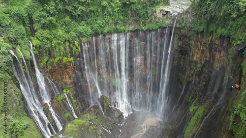 Drone aerial view of Tumpak Sewu Waterfall, East Java, Indonesia. Spectacular dramatic canyon, lush tropical rainforest jungle and majestic volcanic landscape scenery. Famous tourist travel destinatio