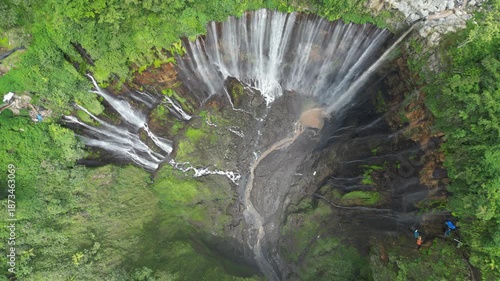 Majestic Tumpak Sewu Waterfall in Indonesia. Powerful water cascades in the tropical Java jungle, drone aerial view. Perfect for travel, nature background, and tourism editorial. Epic landscape.