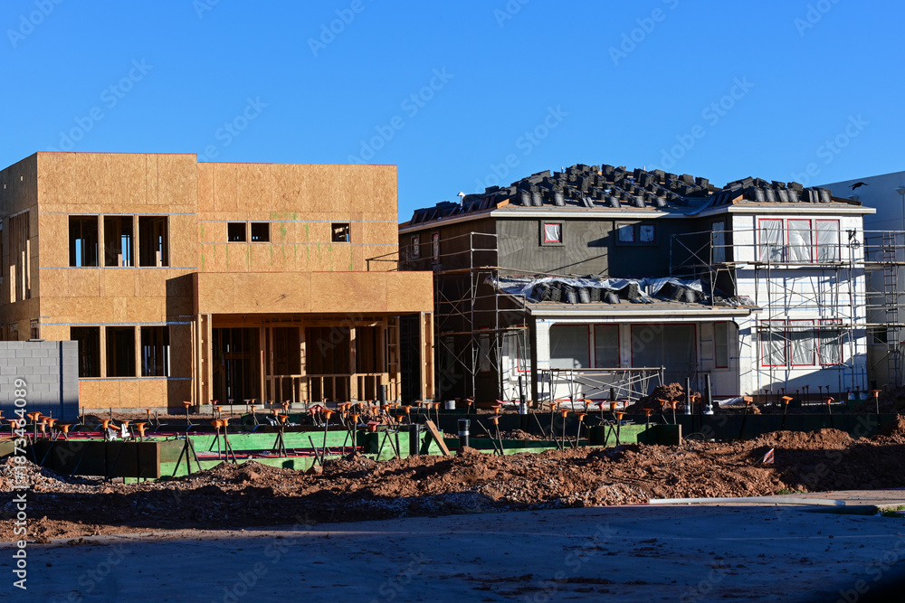 Fototapeta premium Residential structures at various construction stages with lot preparation for a concrete slab, representing housing development, site grading, and building foundation operations