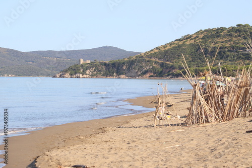 Beautiful scenic view of a wild and empty sandy beach in Albinia, Maremma region, Grosseto province, Tuscany, Italy. Blue sea and Mediterranean coastline under a clear sky.