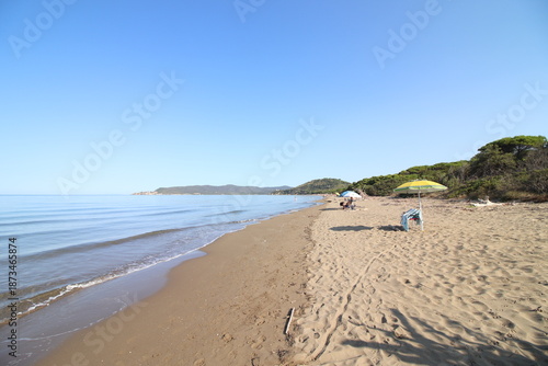 Beautiful scenic view of a wild and empty sandy beach in Albinia, Maremma region, Grosseto province, Tuscany, Italy. Blue sea and Mediterranean coastline under a clear sky.