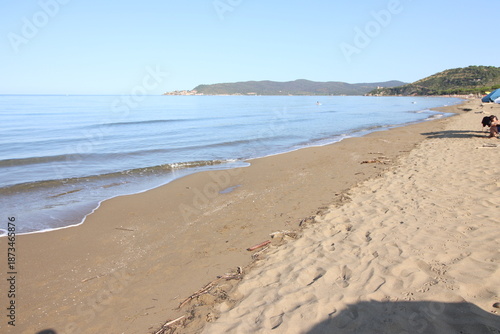 Beautiful scenic view of a wild and empty sandy beach in Albinia, Maremma region, Grosseto province, Tuscany, Italy. Blue sea and Mediterranean coastline under a clear sky.