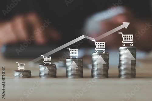 Ecommerce sales growth concept with shopping cart icons on stacked coins and upward arrow graph, online retail revenue increase, business performance, financial success and digital marketing strategy.