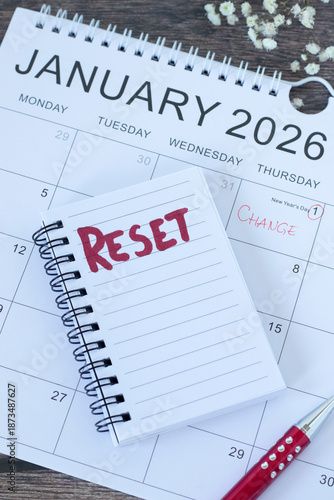 Reset handwritten text in notebook with 2026 calendar. Top view. The concept of change, new beginning, progress, and time management.