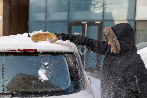 Fotografi Man clearing snow from car using broom in winter