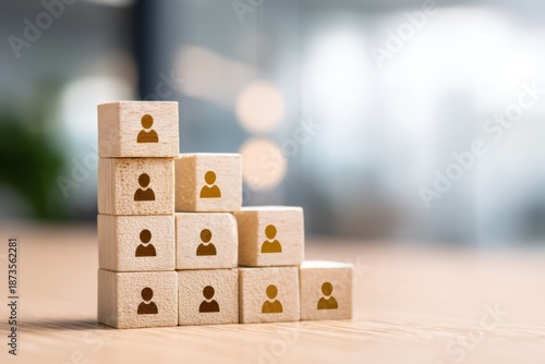 Stacked wooden blocks with people icons, representing workforce structure, team growth, and organizational hierarchy in a business environment.