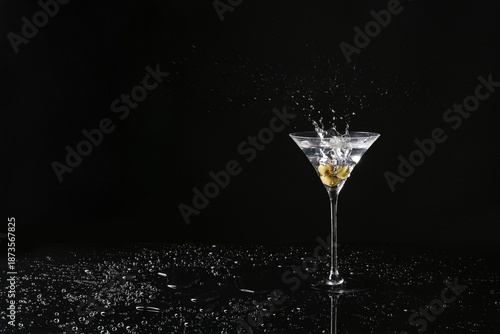 Glass of delicious martini with olives on dark background