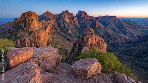Crimson sun sinks below jagged mountain peaks creating a majestic and rugged wilderness vista at dusk