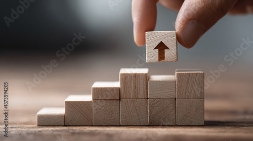 A hand placing the final block with an upward arrow on top of a staircase made of wooden blocks, symbolizing growth and progress