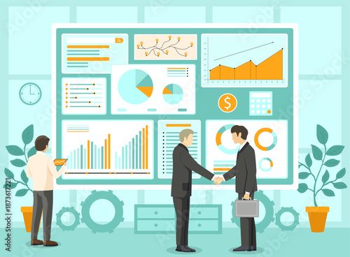 Two people shaking hands in office setting. One person standing near large screen showing graphs and charts