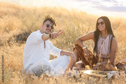 Young couple of hippies with dreadlocks showing victory gesture outdoors