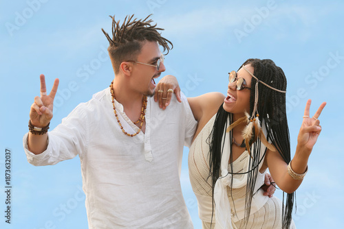 Young couple of hippies with dreadlocks showing victory gesture outdoors