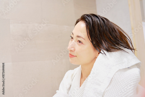 お風呂上がりに濡れている髪をバスタオルで拭く女性　