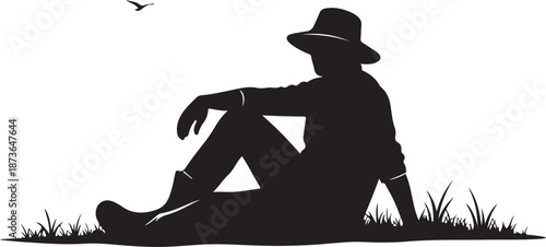 Man sitting in grass wearing hat and boots relaxed