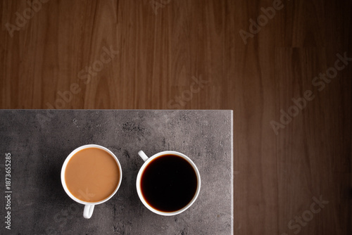 Vászonkép two cups of coffee on a kitchen bench one black one white with a wooden floor in