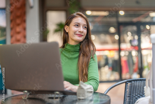 Happy woman freelancer digital nomad working online on laptop, content creator marketer planning social media strategy waiting for travel transport, workation and remote work at cafe coffee shop