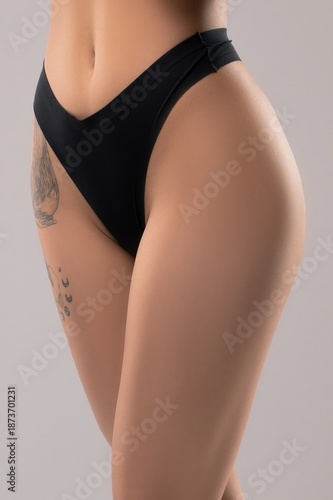 Wallpaper Mural Woman poses in underwear showing her thighs and hips, with a tattoo on one thigh and on a plain background Torontodigital.ca