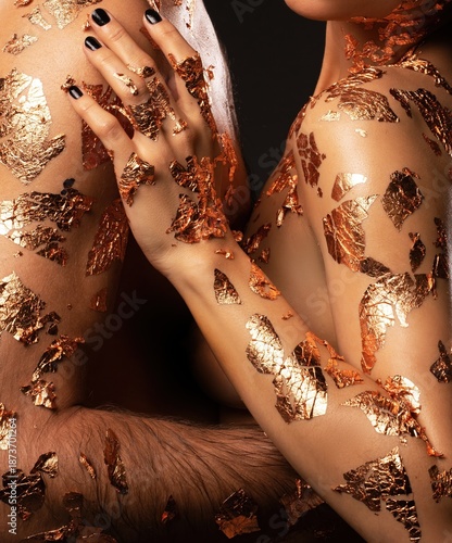 Wallpaper Mural Two figures with gold leaf body art touching each other in a dimly lit space Torontodigital.ca