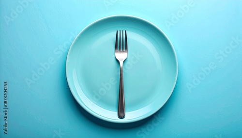 Single fork centered vertically on light blue plate against matching light blue background in minimalist setup.