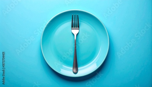Single fork centered vertically on light blue plate against matching light blue background in minimalist setup.