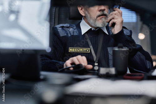 Schilderij op canvas Middle aged Caucasian man working as security guard using two way radio and moni