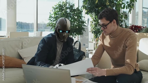 Two business professionals collaborating over documents and laptop in a modern office with natural light.