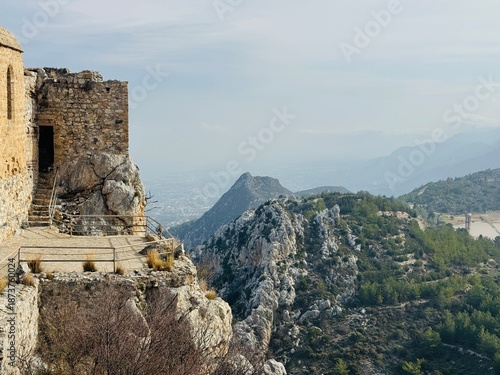 St. Hilarion Castle rising high in the Kyrenia Mountains with the distant coastal city of Kyrenia visible below, featuring dramatic cliffs, medieval stone walls, and sweeping views of northern Cyprus