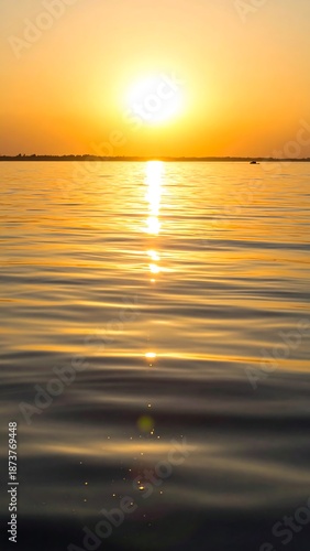 Golden sunset reflecting on tranquil water with rippling surface