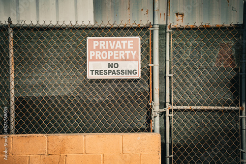 Private property no trespassing sign on a chain link fence with a locked gate
