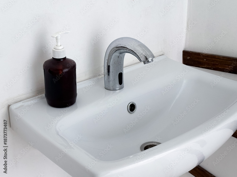 Fototapeta premium Bathroom sink with faucet and soap dispenser.