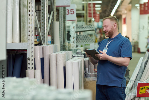 Billede på lærred Caucasian man standing in warehouse aisle holding clipboard and smiling while in