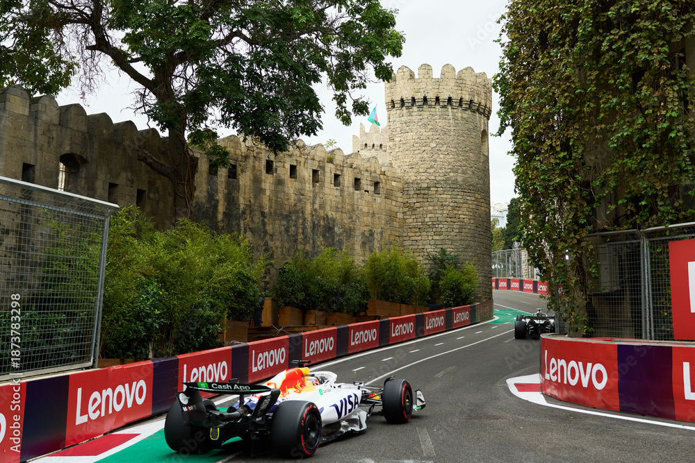 Fototapeta premium BAKU, AZERBAIJAN - SEPTEMBER 20, 2025: A Formula 1 racing car from the Visa Cash App RB team drives through the iconic narrow Old City (Icherisheher) section near the walls