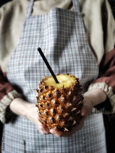 Organic juice from tropical fruit. Close up of person hands with cut Pineapple with black eco stick. Perfect natural juice concept ads poster card cover. 