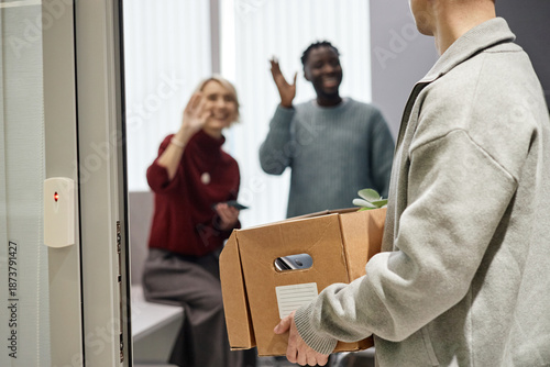 Canvas Print Caucasian young adult man carrying cardboard box with belongings leaving office,