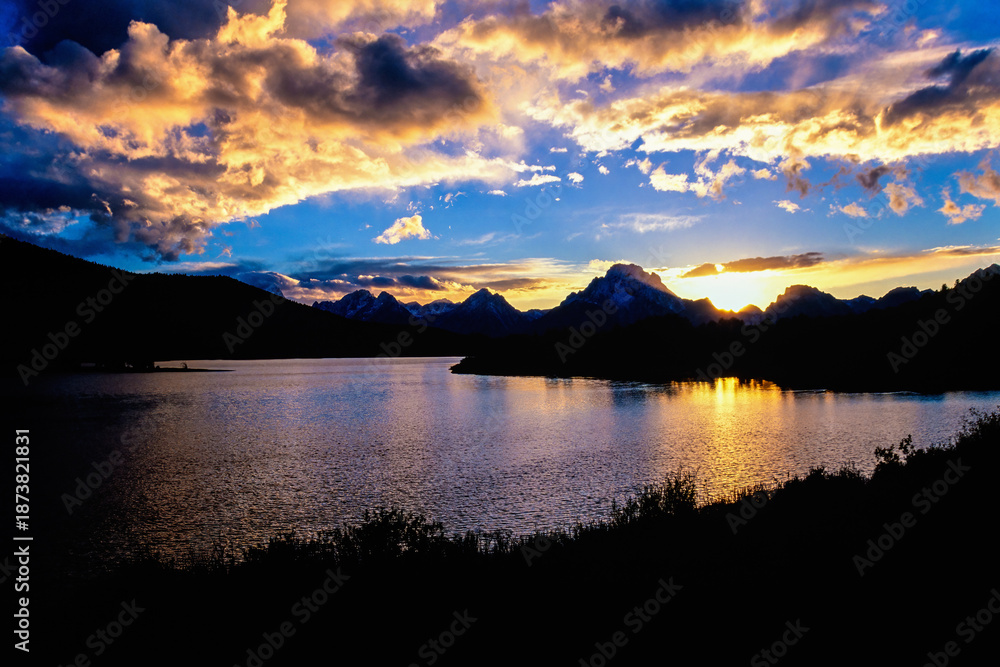 Obraz premium Beautiful sunset by a lake in a mountain landscape