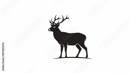 Silhouette of a majestic stag with large antlers standing on a small hill.